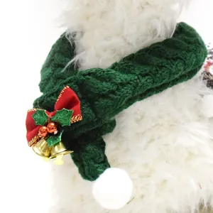 Close-up of a green knitted Christmas pet scarf with red bow and gold bells for cats