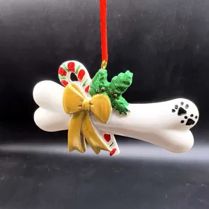 Décoration de Noël en résine en forme d'os de chien avec nœud doré et empreinte de patte.