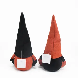Rear view of two Halloween plush gnomes with tall pointed hats in orange and black