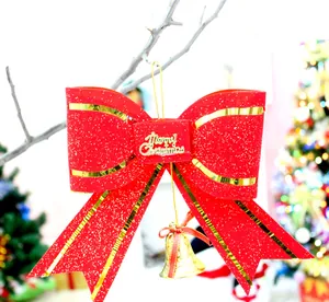 Detailed view of red glitter Christmas bow with gold bell and Merry Christmas sign.