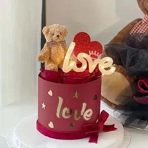 Close-up of teddy bear and glowing LED love sign in a red rose gift box decoration.
