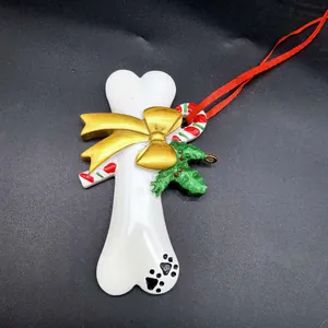 Détail d'un ornement de Noël en résine en forme d'os avec nœud doré.
