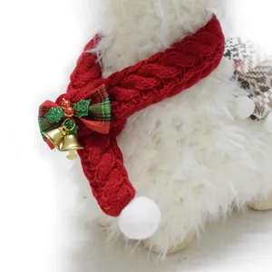 Close-up of red knitted Christmas pet scarf with plaid bow and festive gold bells