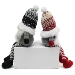 Detailed view of two Nordic knitted Christmas gnomes sitting together on a white block.