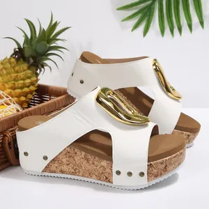 Side view of white peep-toe platform wedge sandals featuring a large gold metal buckle.