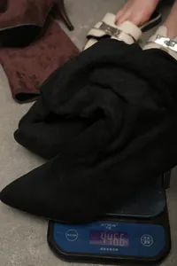 Slouchy black suede pointed-toe boot weighed on a digital scale showing 446.6g