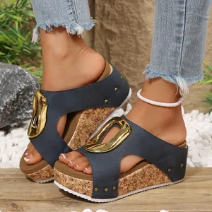 Close-up of navy blue platform wedge sandals with large gold buckle and cork texture