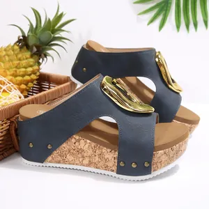 Close-up of navy blue wedge sandals featuring a large gold buckle and cork texture sole