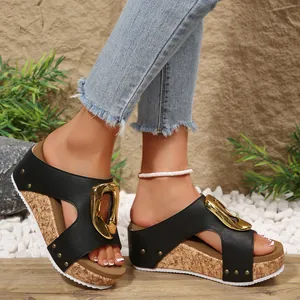 Detailed side view of women's black wedge sandals with a large decorative gold buckle.