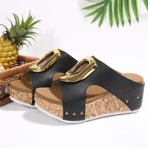 Close-up of stylish black wedge sandals with a large gold buckle and cork platform sole
