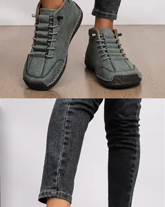 Detailed view of grey hand-stitched casual ankle boots with denim jeans for autumn outfits.