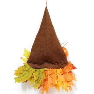 Gedetailleerd beeld van herfstkabouter met stoffen hoed en levendige kunstmatige esdoornbladeren.