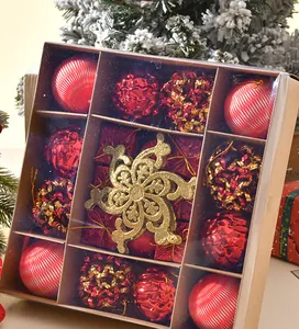 Nahaufnahme des Weihnachtsdekorationssets mit roten Kugeln und goldenem Stern in Kraftbox