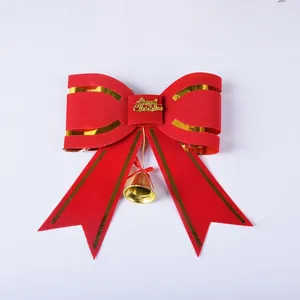 Close-up detail of a red and gold Christmas bow with a gold bell and lettering