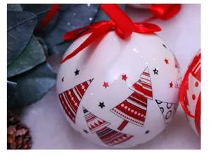 Détail d'une boule de Noël blanche de 7,5 cm avec motifs sapins rouges et ruban
