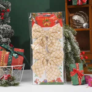 Close-up of two gold lattice Christmas bows in retail packaging with festive props