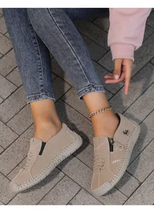 Primer plano de zapatos informales beige cosidos a mano con cremallera lateral