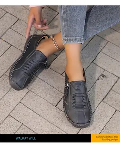 Detalle de zapatos planos de cuero cosidos a mano con cremallera en suelo de piedra