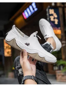 Primo piano di mocassini in pelle bianca traspirante con logo ariete e design slip-on
