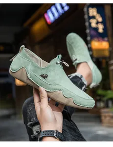 Primo piano di mocassini casual in pelle scamosciata verde con cuciture e logo
