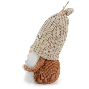 Close-up detail of a handmade faceless gnome figurine with a beige knitted hat and white beard