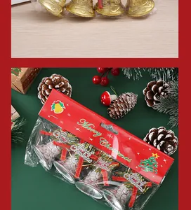 Close-up of silver Christmas bell decorations in festive red packaging on a green background.