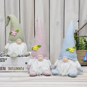 Close-up detail of three pastel spring Easter gnomes with knitted hats in green, pink and blue