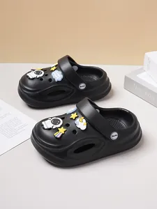 Close-up detail of black children's clogs featuring cute astronaut and star cartoon charms