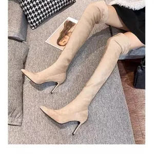 Detailed view of beige suede over-the-knee boots with pointed toe and stiletto heel.