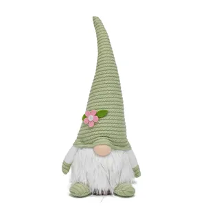 Front view of a spring-themed Easter gnome with a green knitted hat and pink flower decoration.