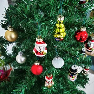 Detailweergave van diverse glazen kerstversieringen aan een groene boom.
