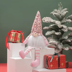 Close-up of a pink sequined Christmas gnome doll sitting among festive gift boxes