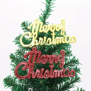 Close-up of gold and red electroplated Merry Christmas ornaments hanging on a green tree