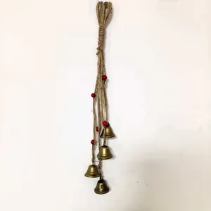 Detailed view of vintage rustic metal bells hanging on a knotted jute rope with small red beads
