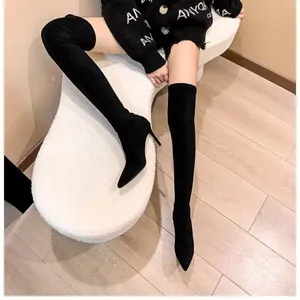 Detailed view of black suede over-the-knee boots with pointed toe and high heel.