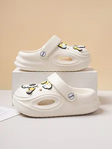 Detail view of cream casual clogs featuring cute astronaut and rainbow charms on box