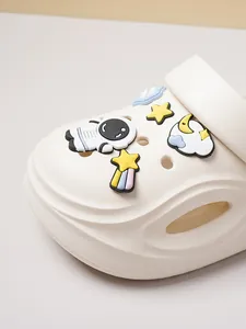 Close-up of white clog shoes with astronaut and star themed PVC charms.