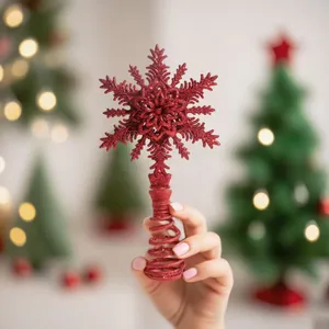 Detailansicht einer roten Glitzer-Schneeflocke als Weihnachtsbaumspitze in der Hand.