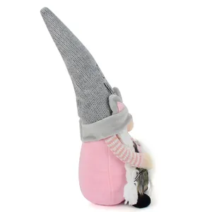 Side view of a cute pink and grey plush cat gnome doll with knitted hat details