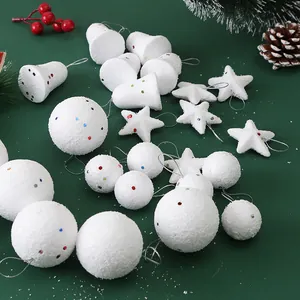 Macro view of white foam Christmas ornaments including bells, stars, and glitter balls on green.