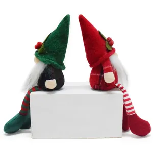 Pair of plush Christmas gnomes with dangling legs sitting on a white rectangular prop box