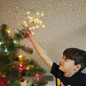 Ein Kind setzt einen leuchtenden goldenen Stern aus Eisendraht auf den Weihnachtsbaum.