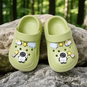 Comfortable light green kids' EVA clogs with cute astronaut and star charms on rock background