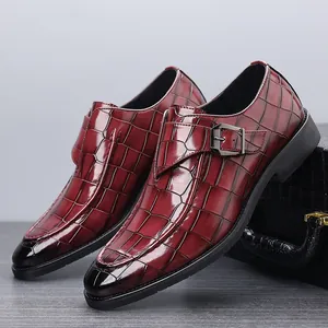 Detailopname van bordeauxrode monk-schoenen met krokodillenpatroon en metalen gesp