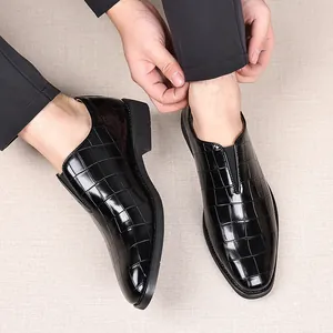 Primer plano de mocasines negros para hombre con diseño de rejilla usados por un modelo.