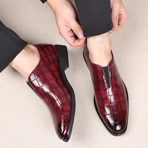 Detalle de mocasines para hombre en burdeos con textura de cocodrilo y punta afilada