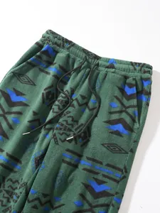 Detailed view of green fleece pants with ethnic geometric pattern and drawstring waist
