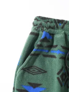 Detailed view of green fleece sweatpants featuring unique ethnic geometric patterns and drawstring
