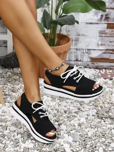 Detailed view of black lace-up platform sandals featuring a chic peep-toe design and white laces
