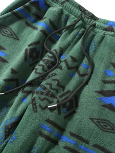 Close-up of green fleece pants featuring ethnic geometric patterns and drawstring detail